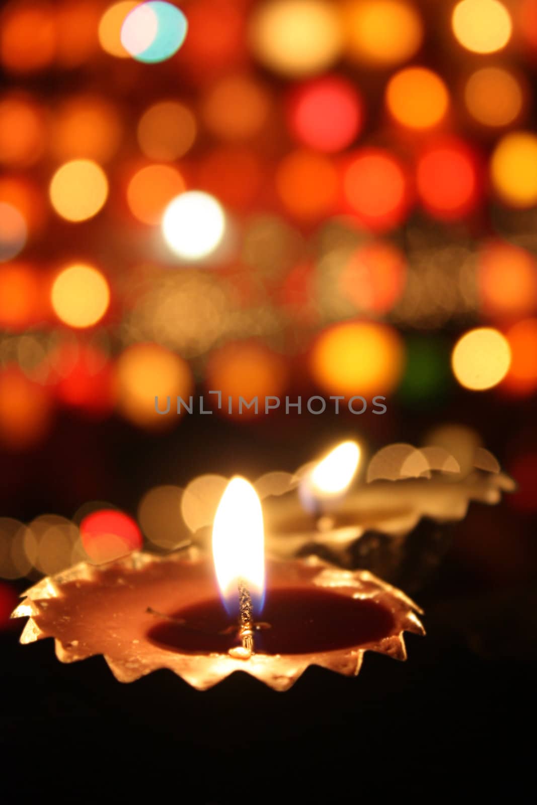 Traditional lamp lit on the blur of colorful lights on the festive occassion of Diwali often known as 'The Festival of Lights'.