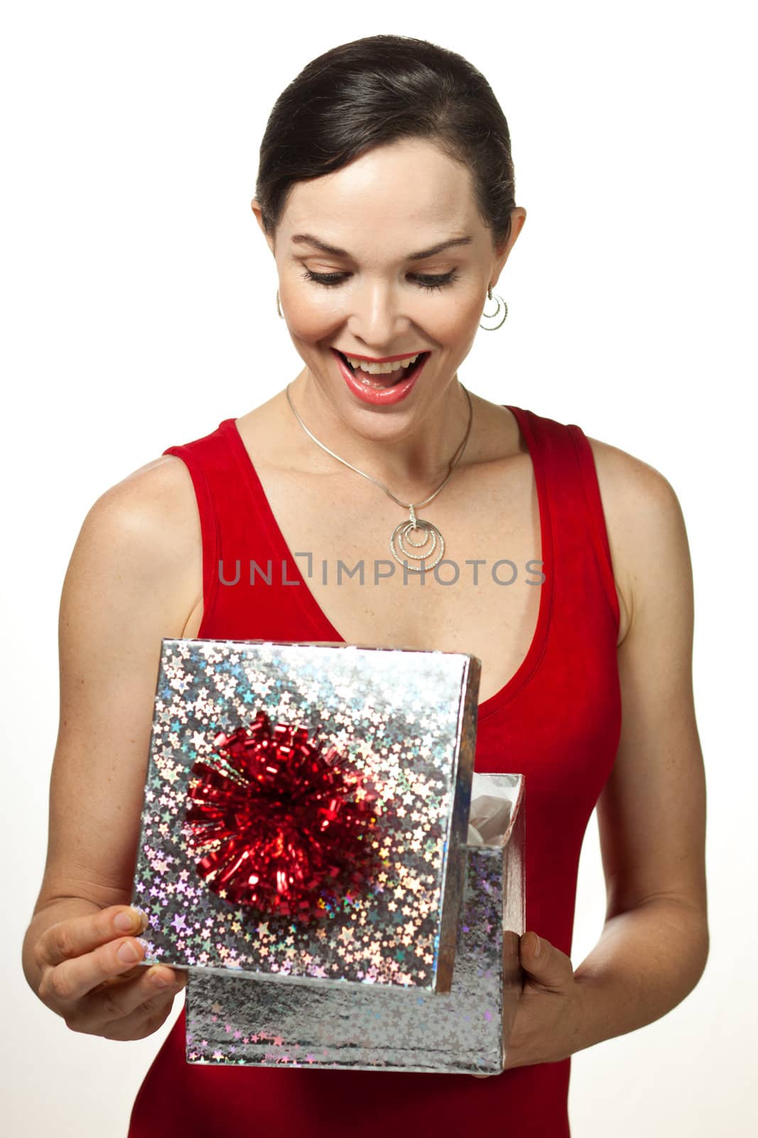 Very attractive young woman smiling and looking in a gift box. Isolated on white