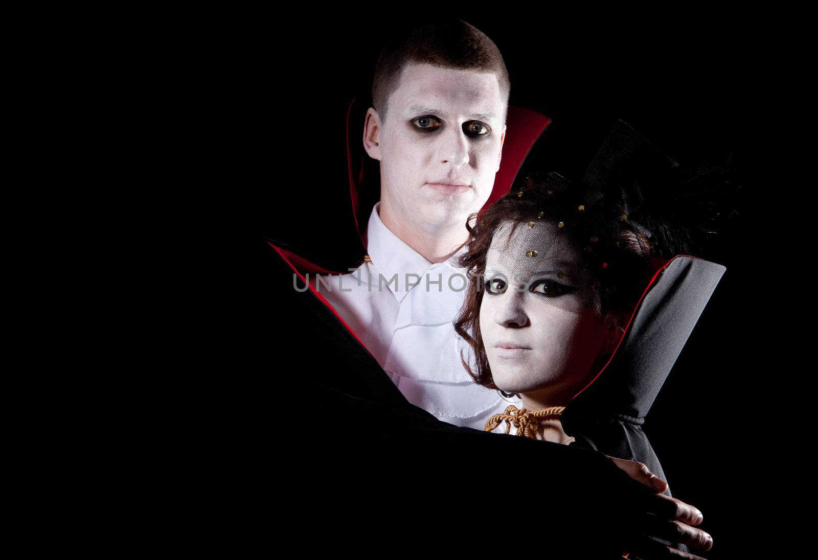 a young vampire couple posing together black background