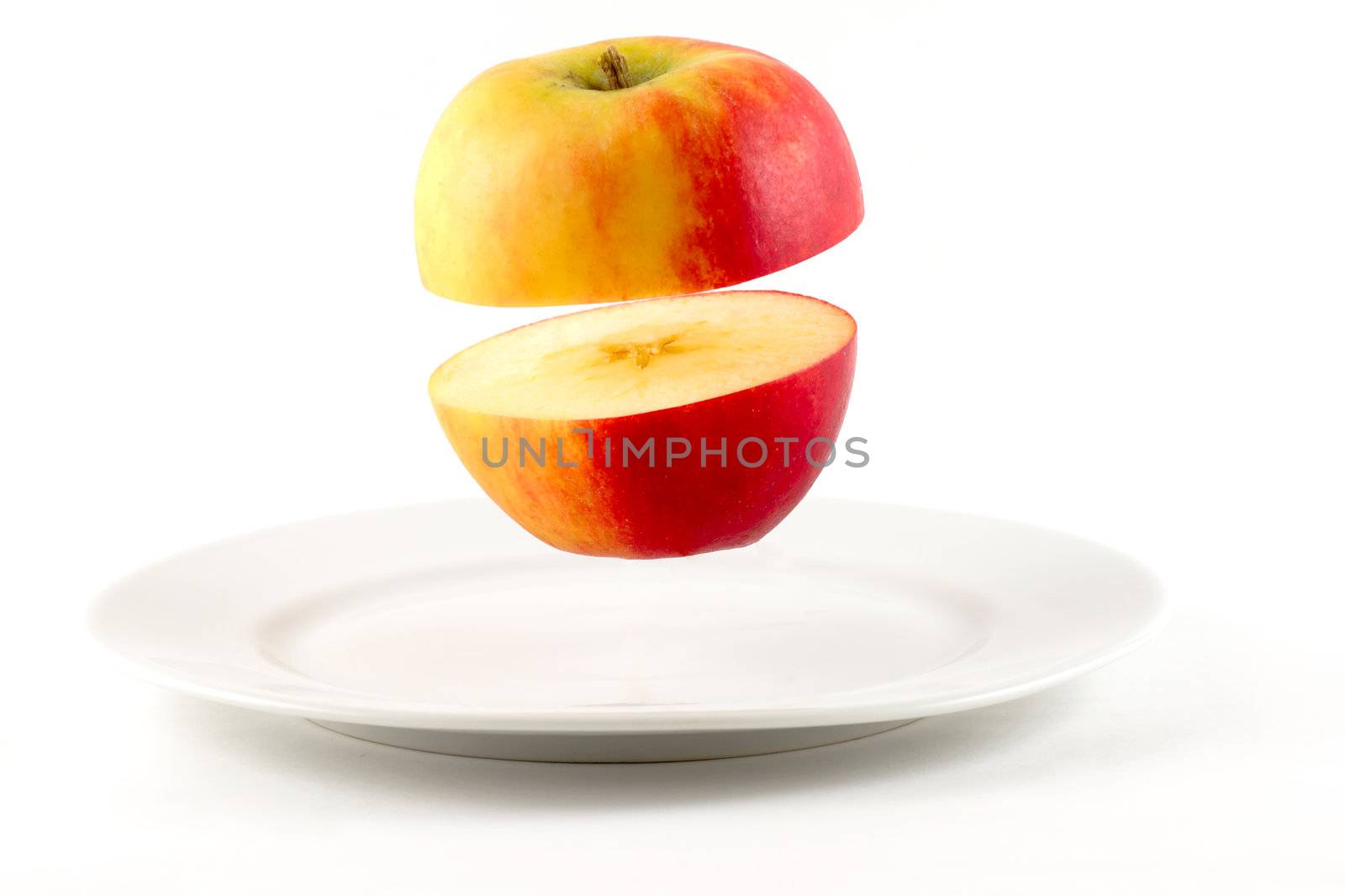 Sliced Apple hovering over white plate