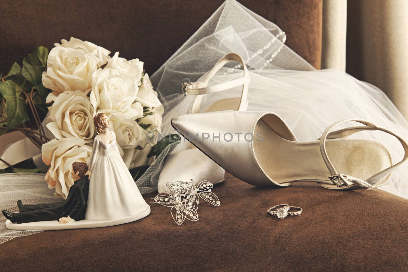 Bouquet of white roses, rings and satin wedding shoes on chair
