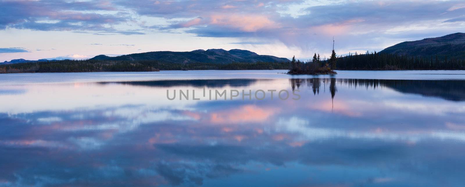 Calm lake reflecting sky at sunset, Twin Lakes, Yukon Territory, Canada.