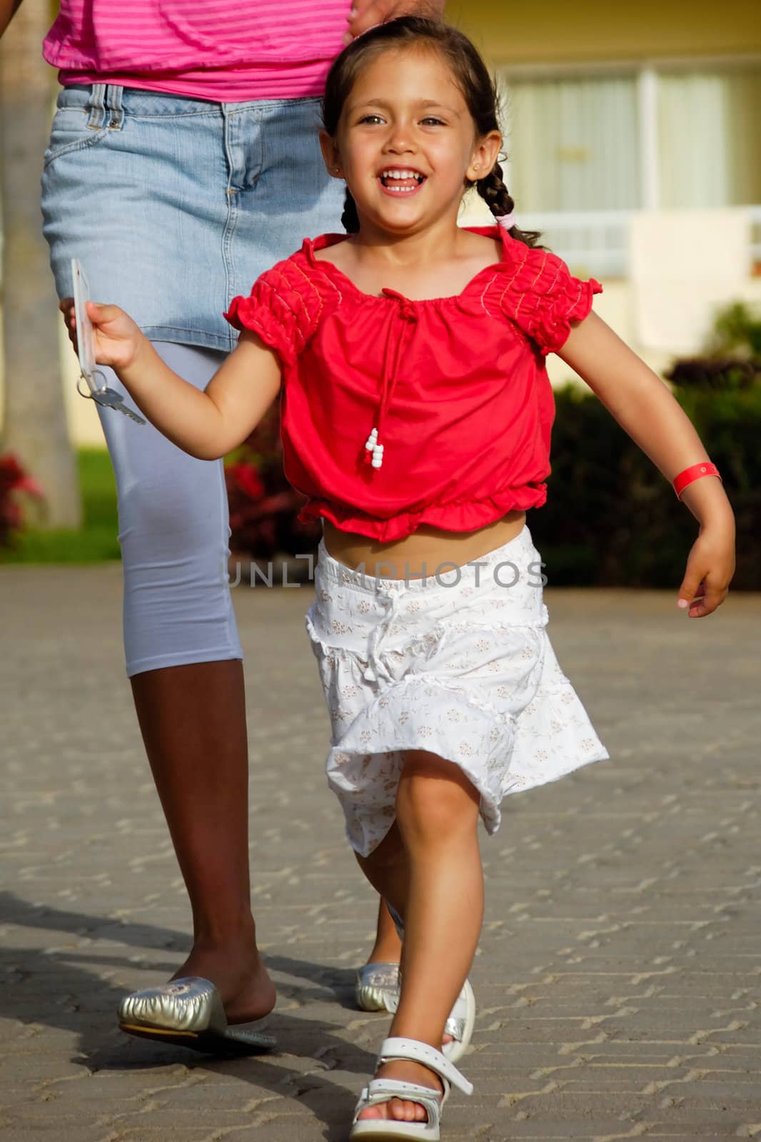 A happy child is running while holding a hotel key in her hand
