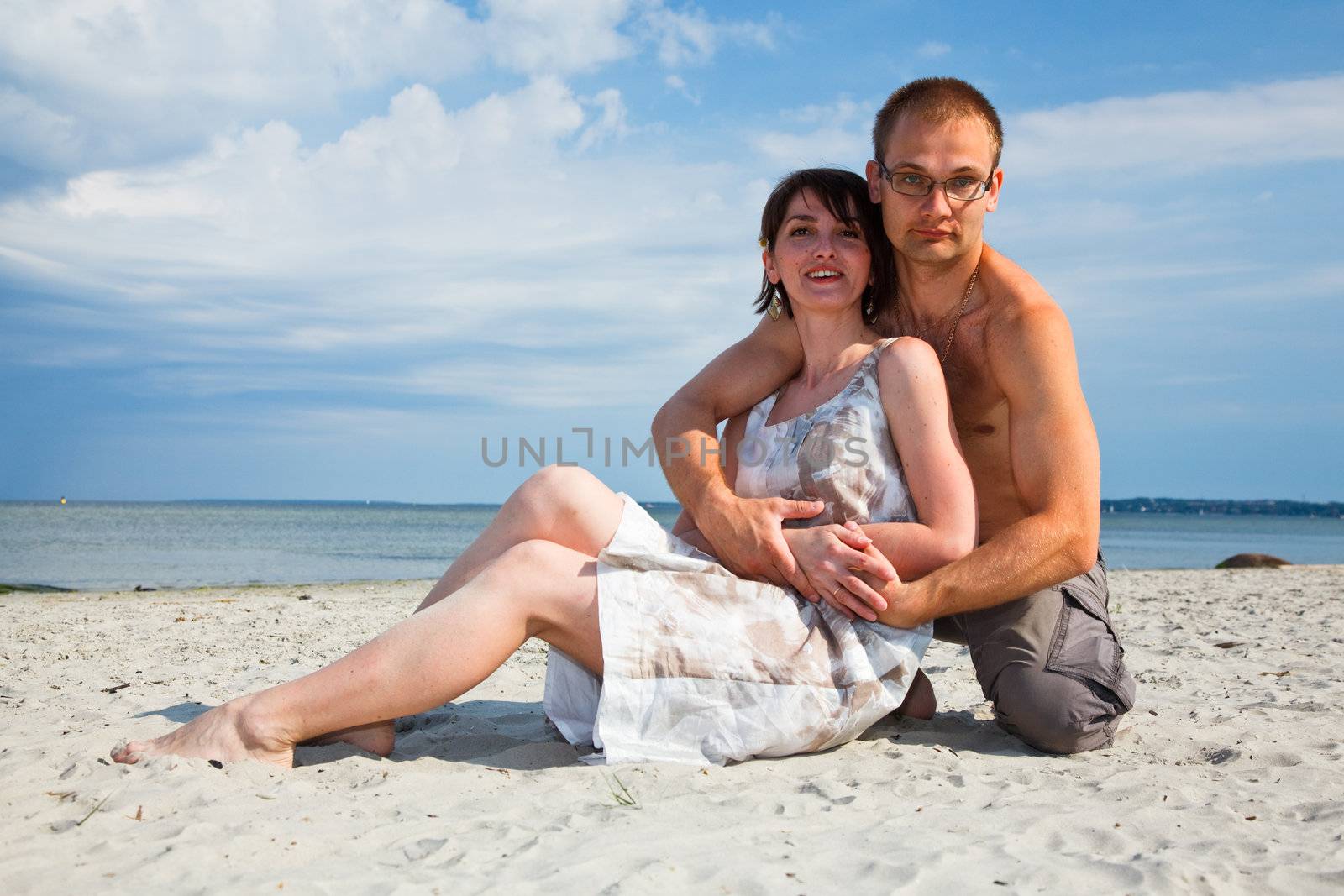A young couple sitting together on the beach