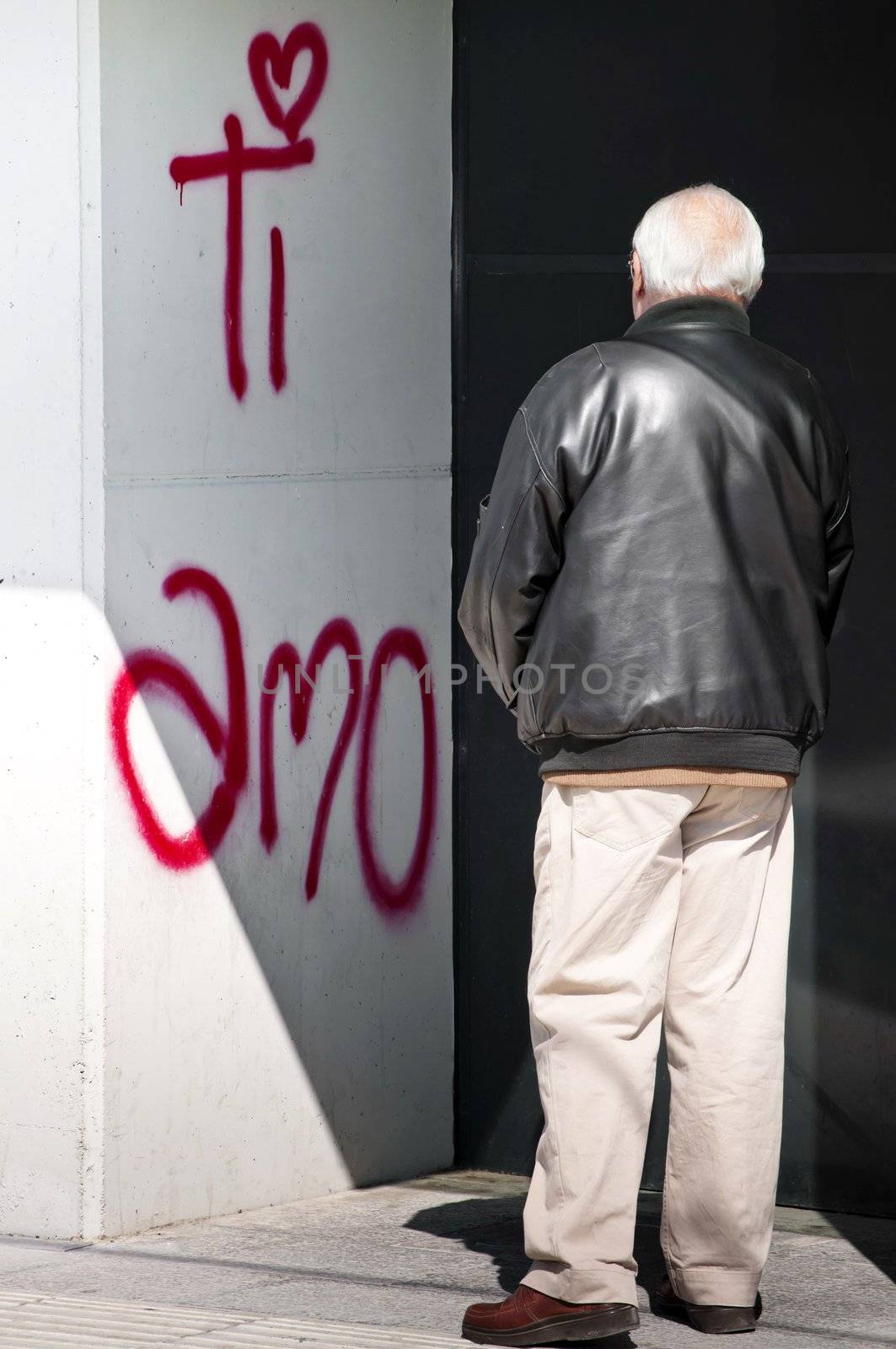 Senior looking to a love text over a white urban wall