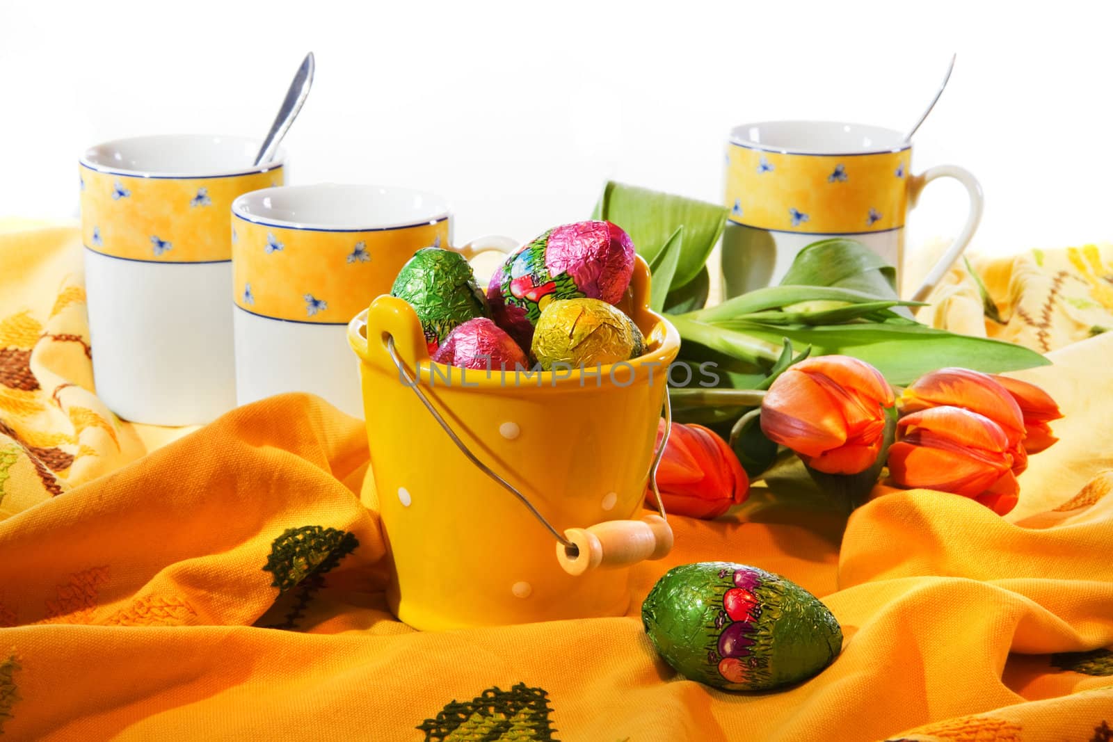 Easter decoration - small bucket with chocolate eggs, table-cloth and mugs