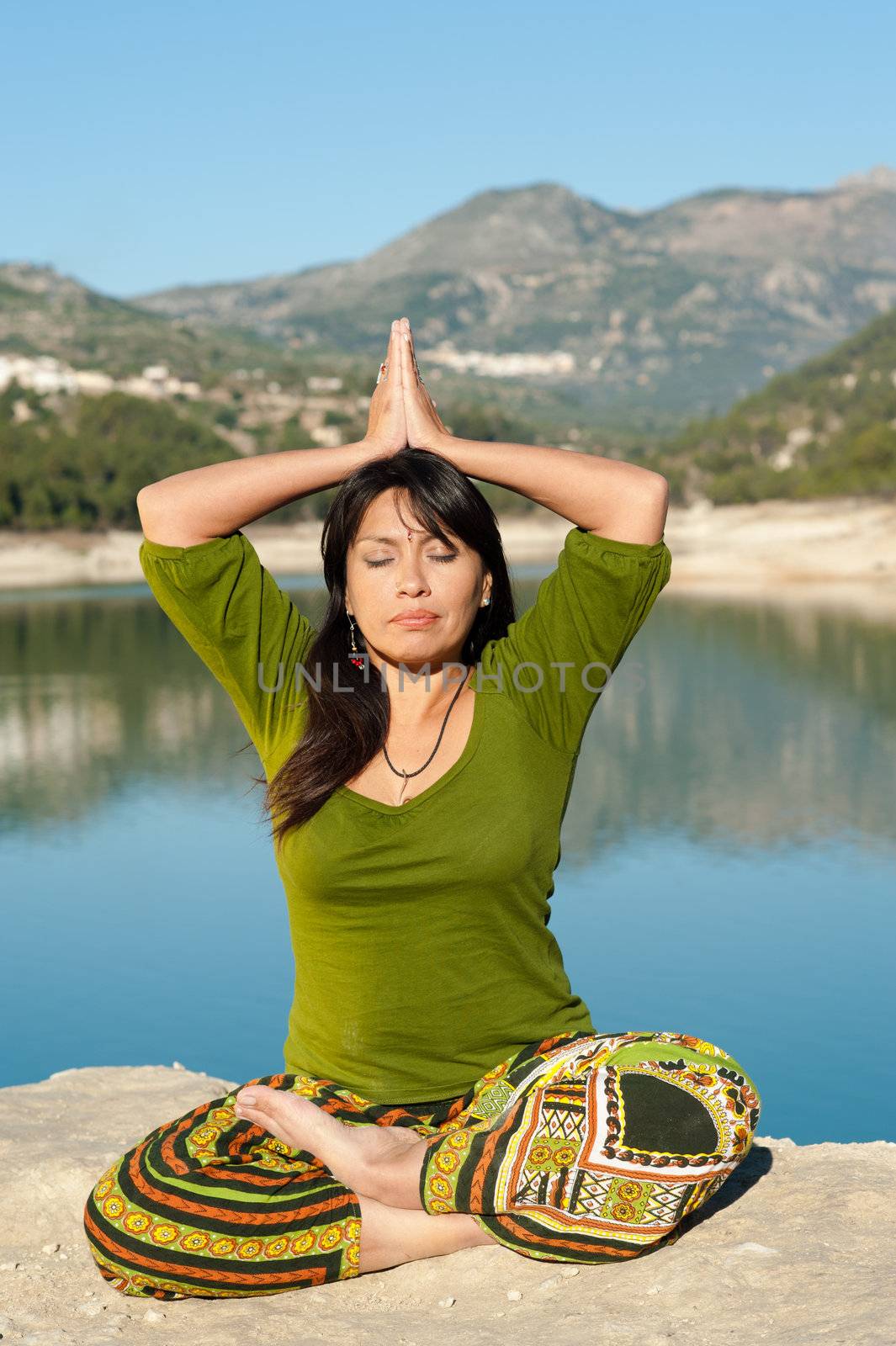 Hispanic woman enjoying early morning yoga on the shores of a lake