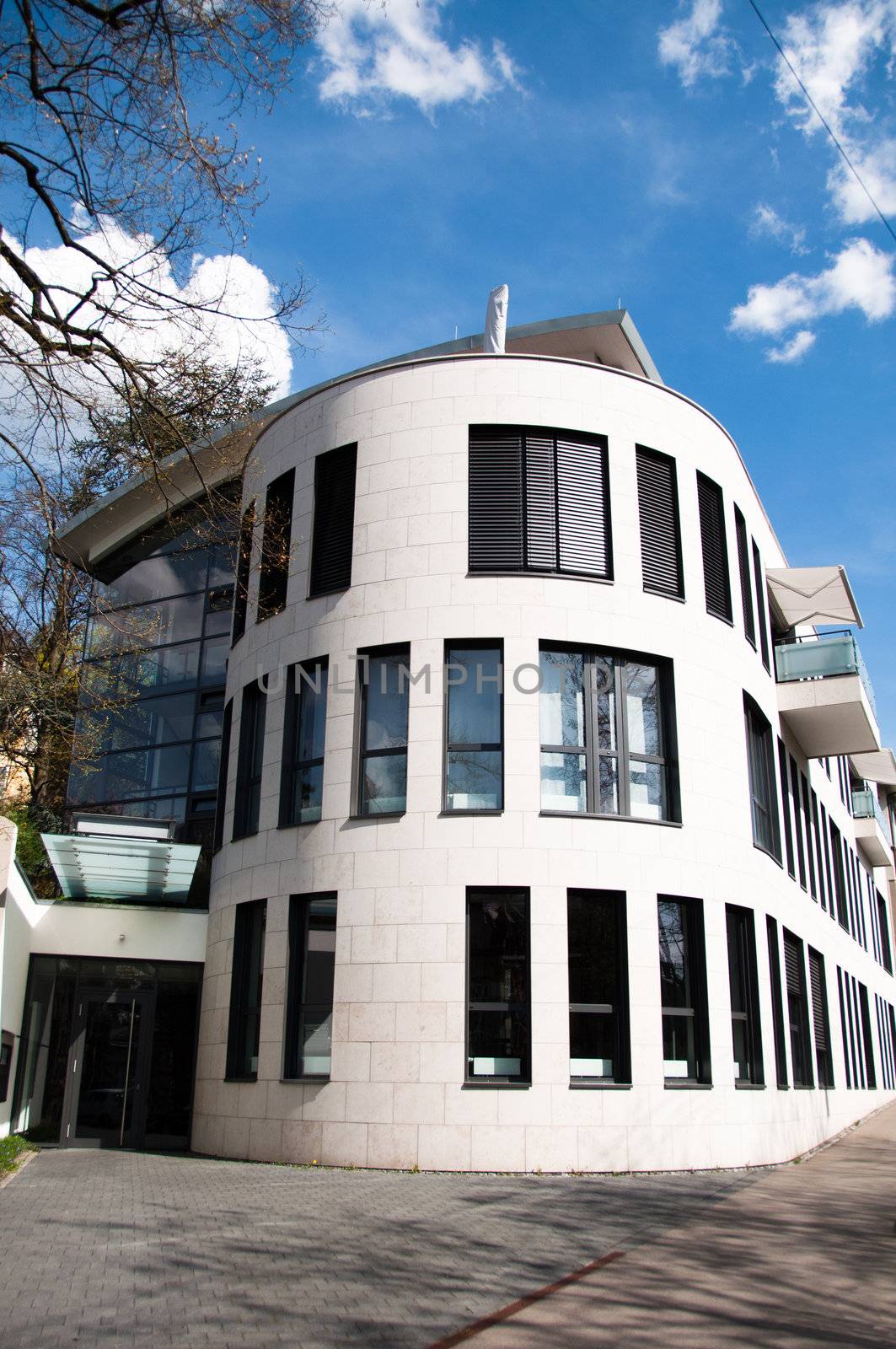 Modern white and gray architecture featuring square column glass panels and great cloudy blue sky