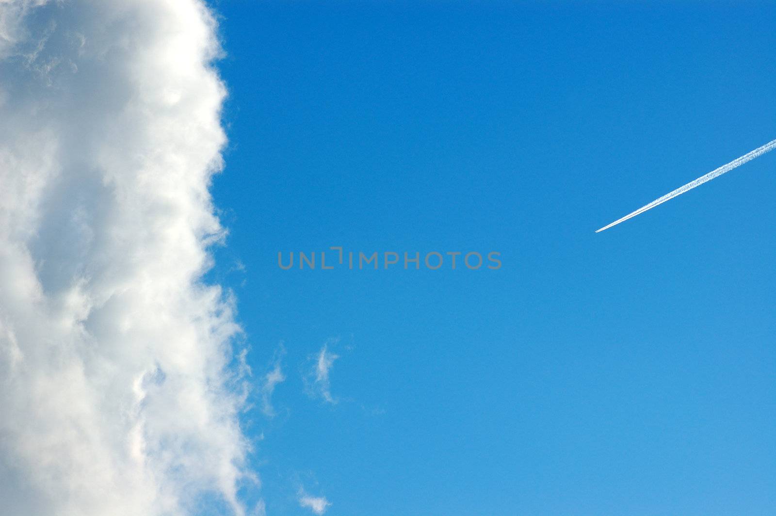Cloud against a blue sky and airplane smoke trail.