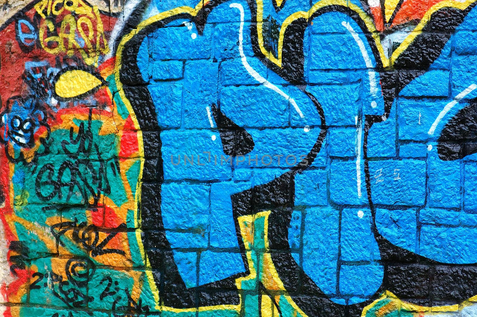 Rough wall surface covered with colorful graffiti. Urban street art background.