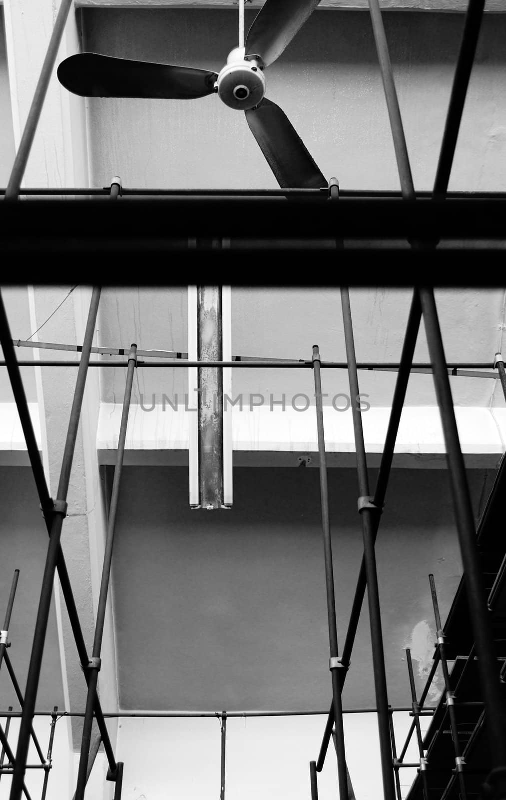 Ceiling fan and empty shelves inside an abandoned factory. Black and white.