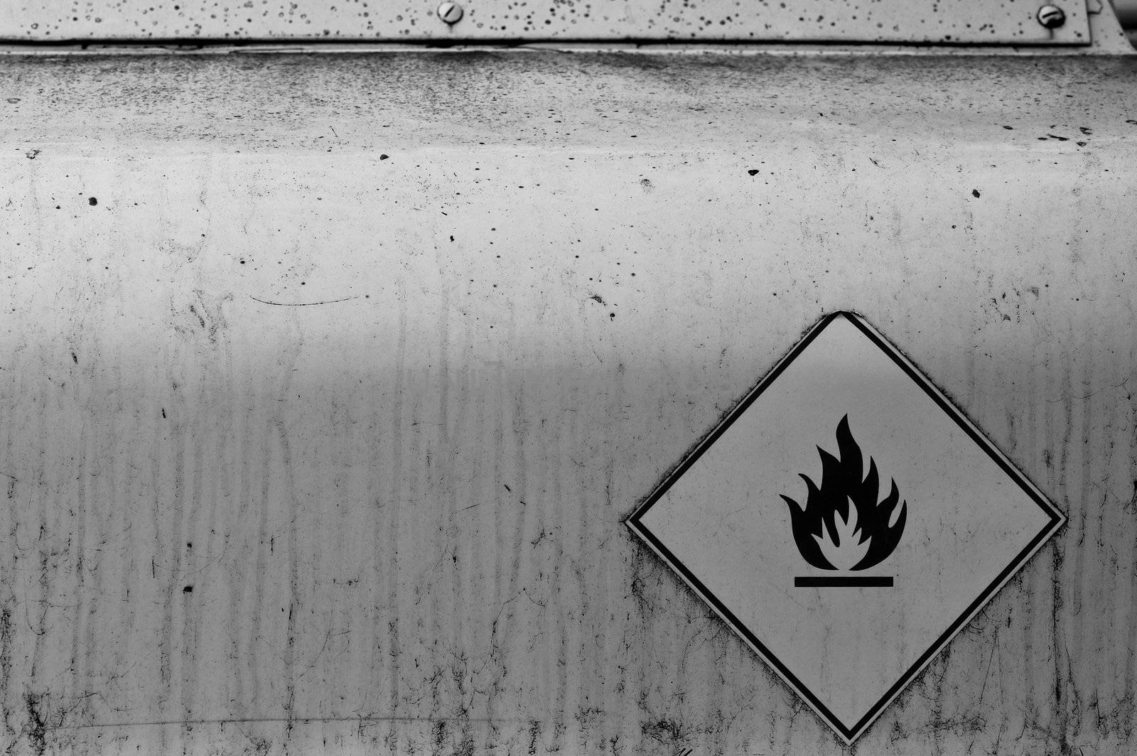 Flammable material weathered warning sign on rusty metal surface. Black and white.