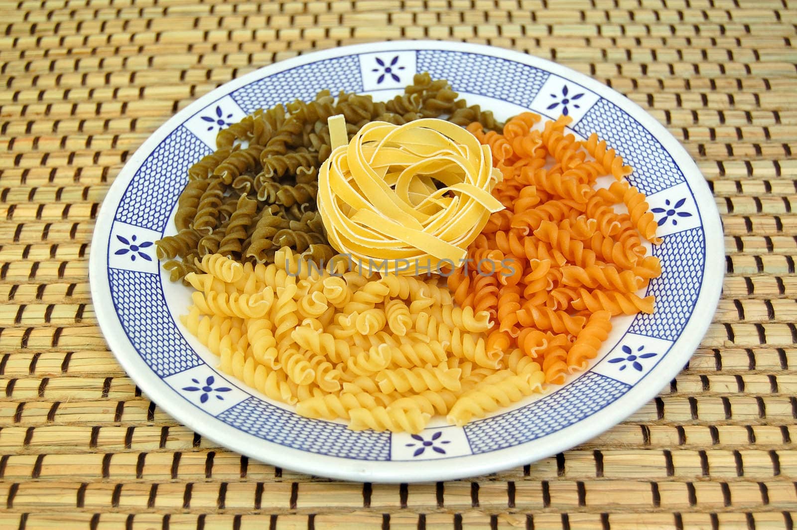 Plate with three flavors of fusilli pasta. Italian food background.