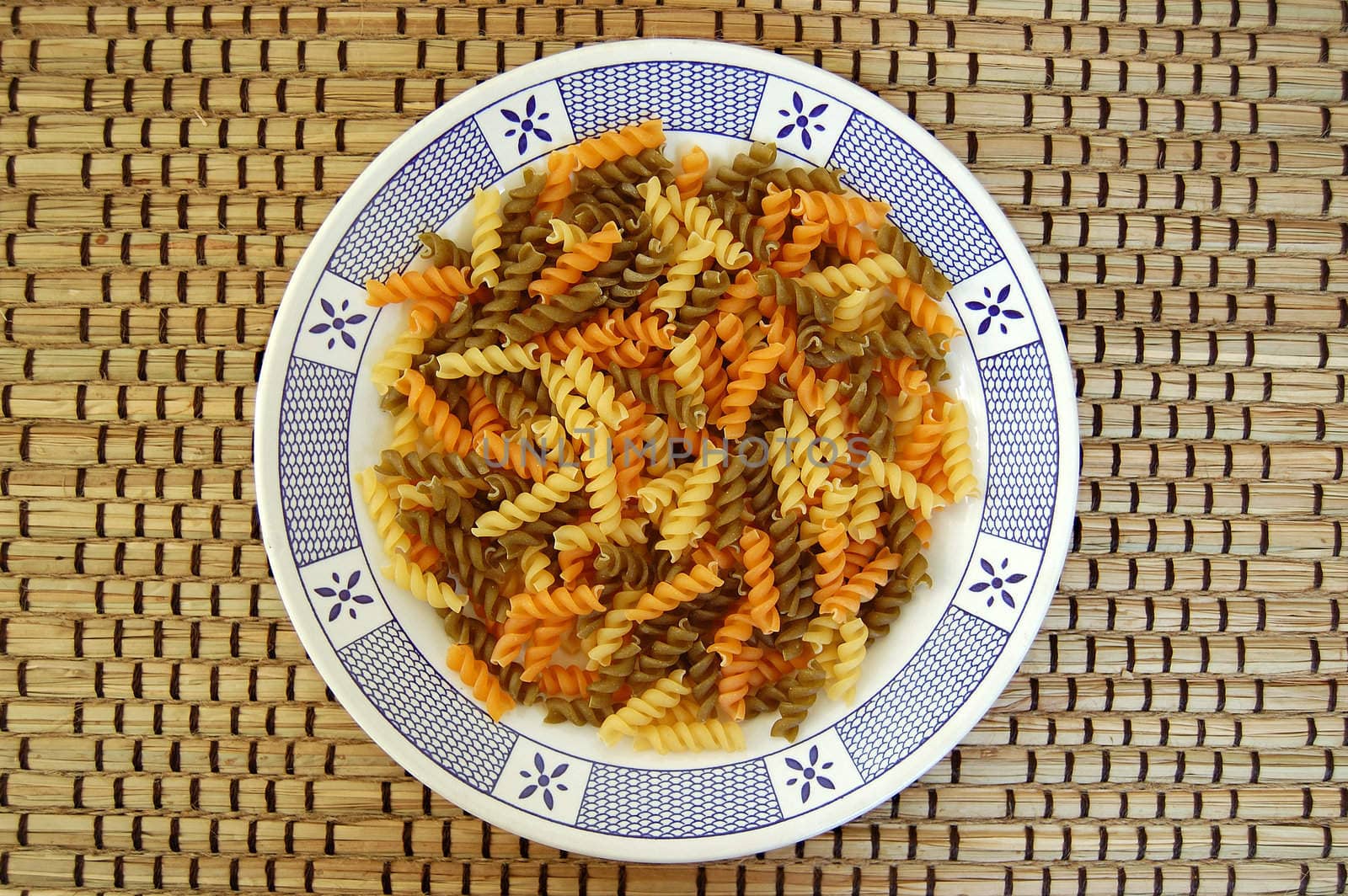 White plate with three flavors of fusilli pasta. Italian food background.