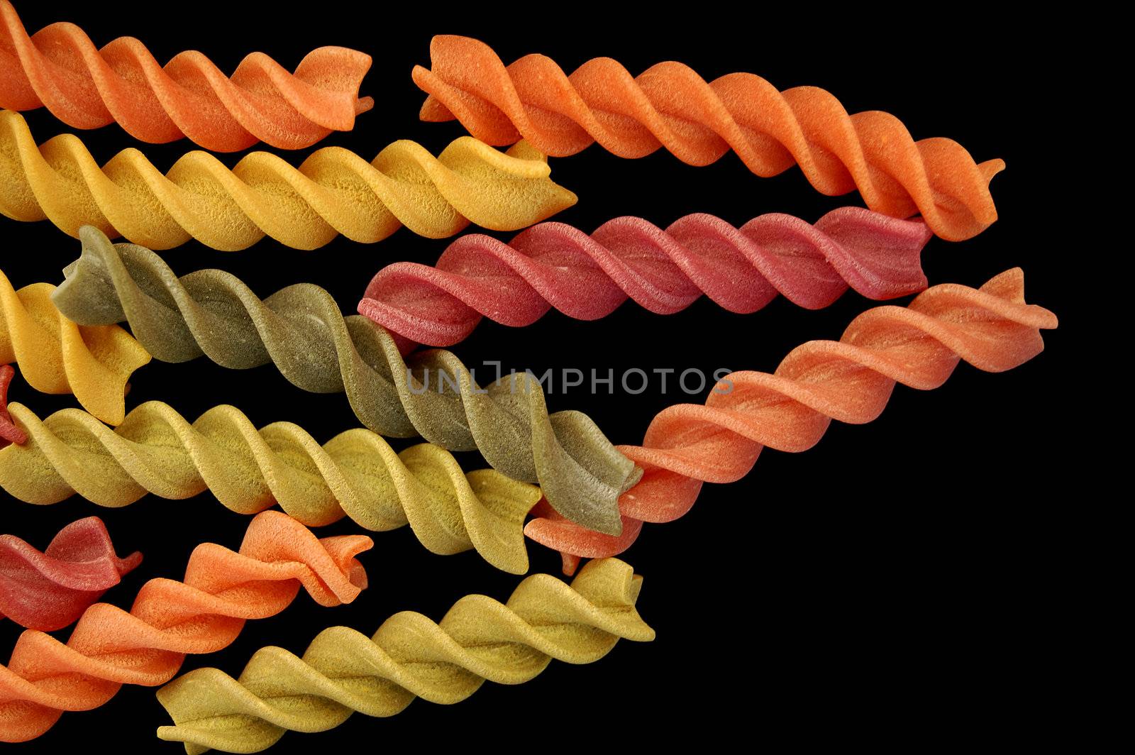 Multi colored fusilli twirls pasta against a black backgrround.