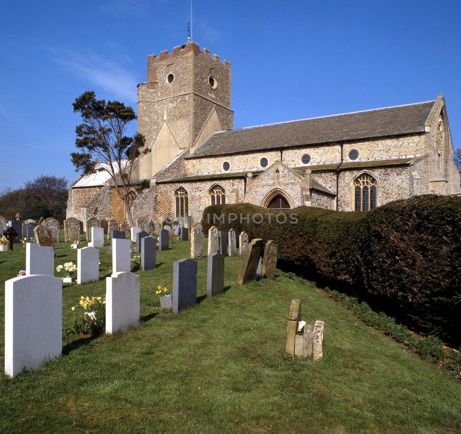 English church set in the country with graveyard and hedge leading to the entrance