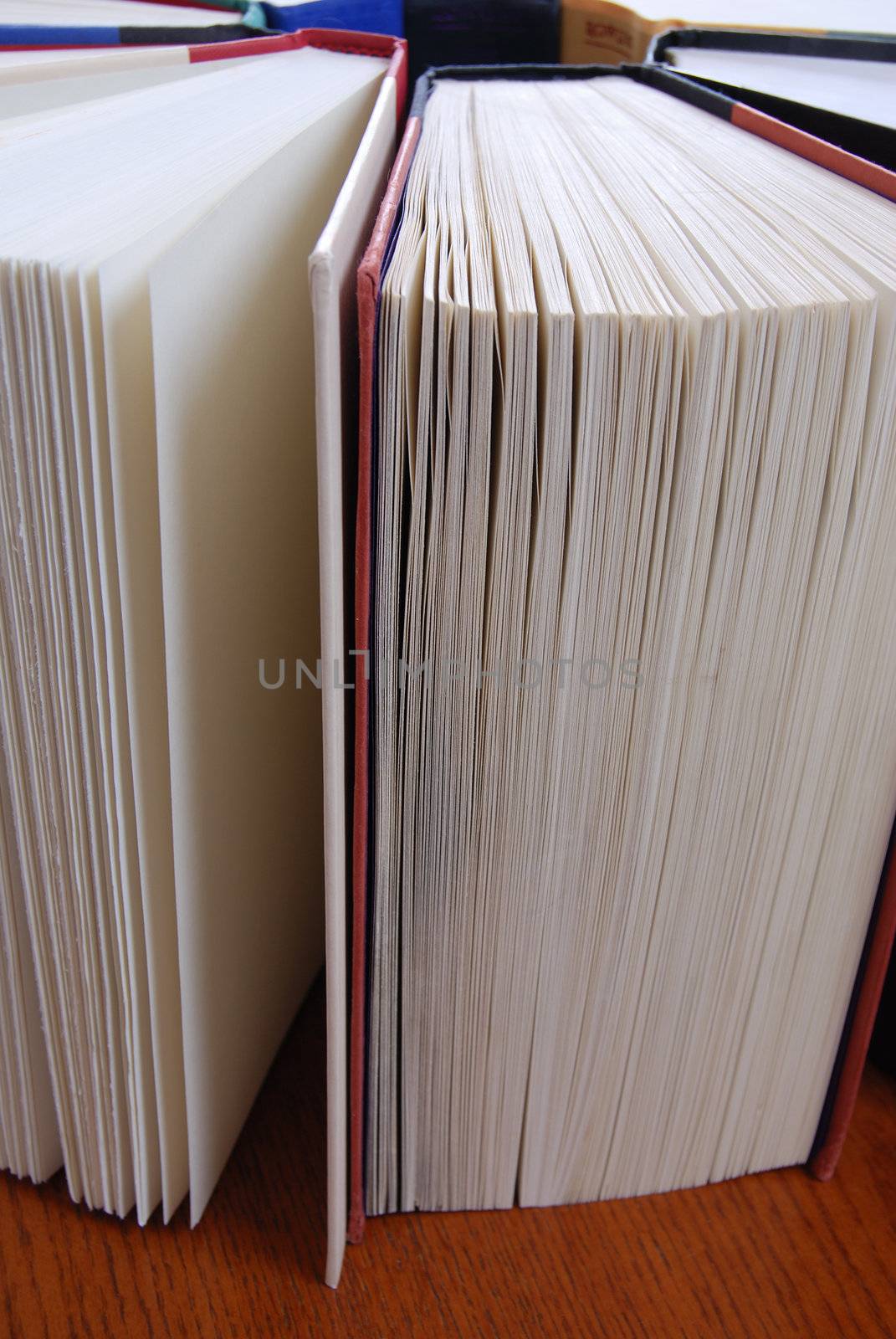 Vertical image of a group of books standing up in a circular formation on a wooden table.