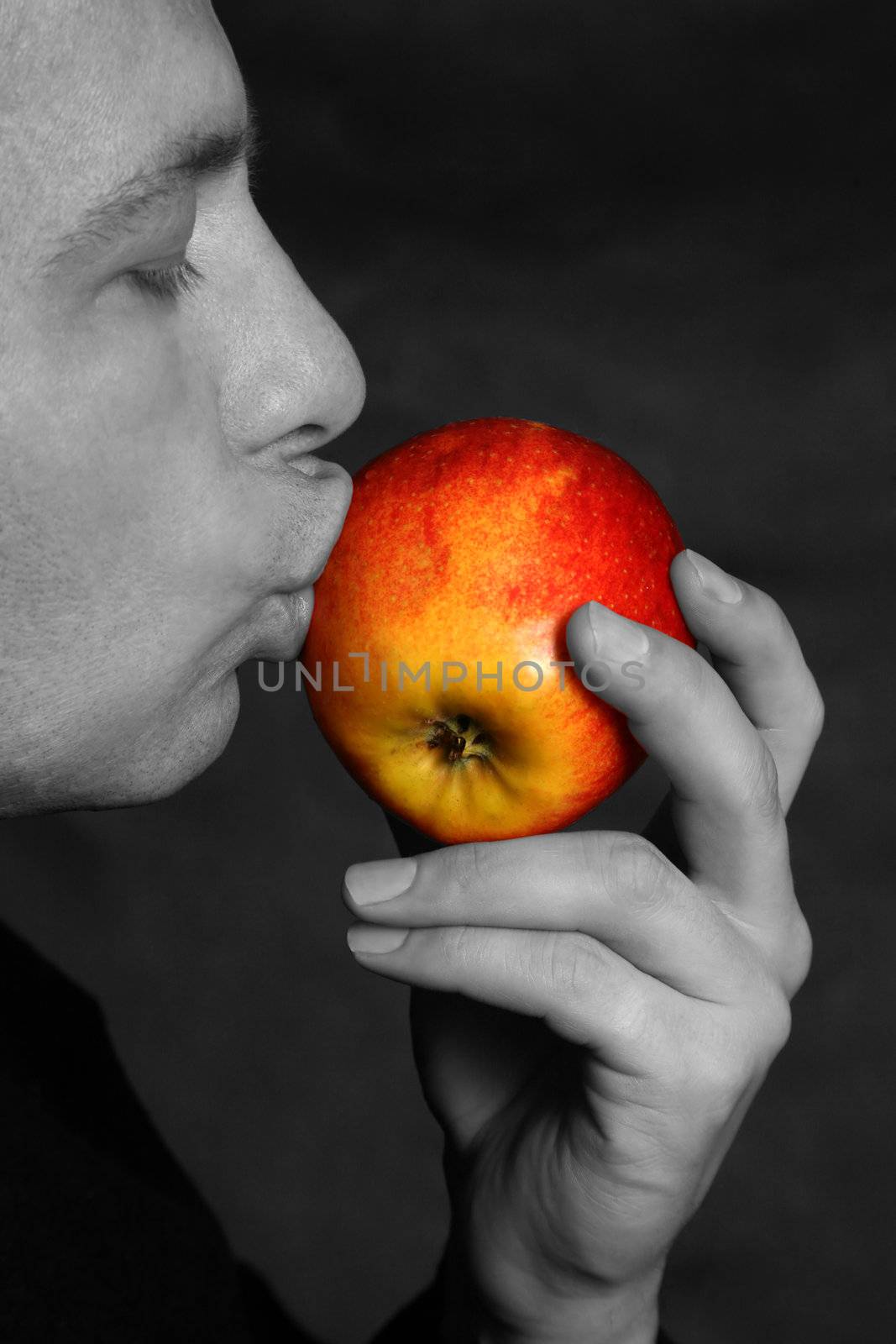 The man concerns lips of a red apple