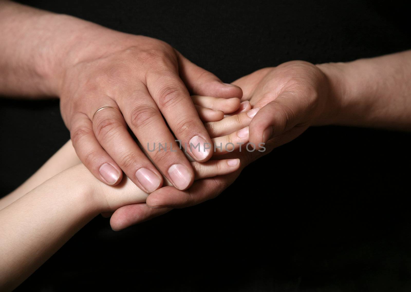 Hand of the adult person and hand of the small child on a dark background