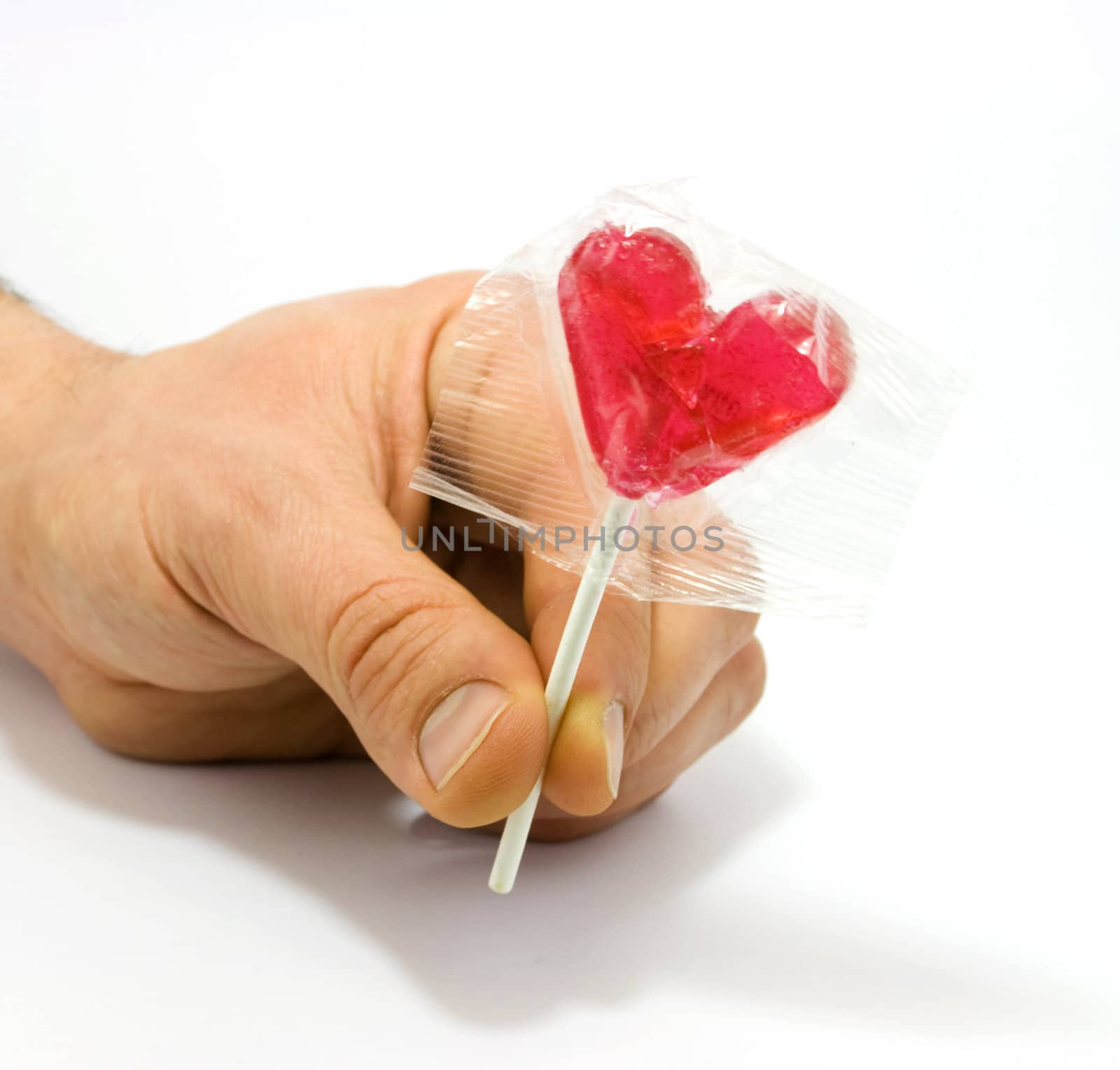 Human hand holding heart shaped candy isolated on white