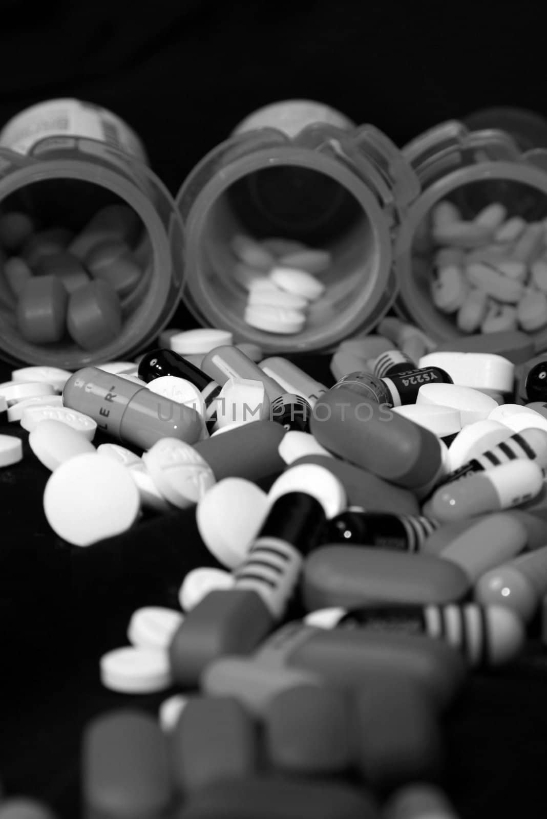 Drugs, prescriptions medicines, pills, and bottles pouring out onto black background