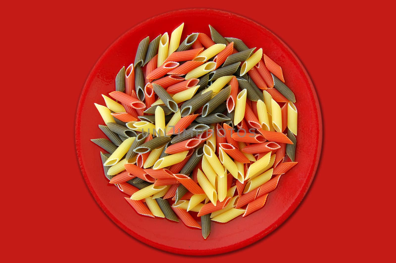 Red plate with three flavors of penne pasta. Italian food background.