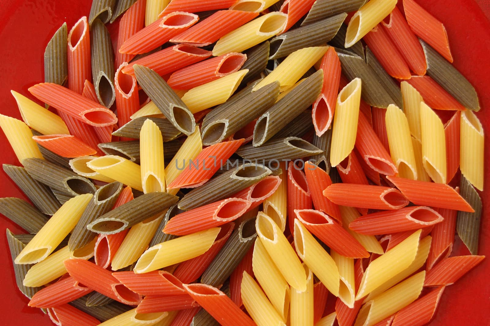Three colored pens pasta. Italian food on red background.