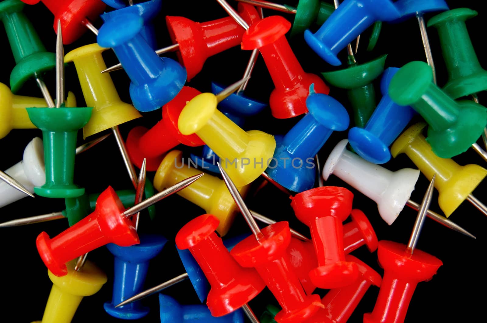 Multicolored office push pins pattern on black background. 