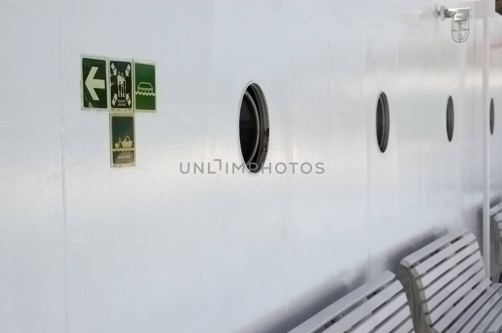 Safety signs on the deck of a ship indicating direction to life saving equipment.