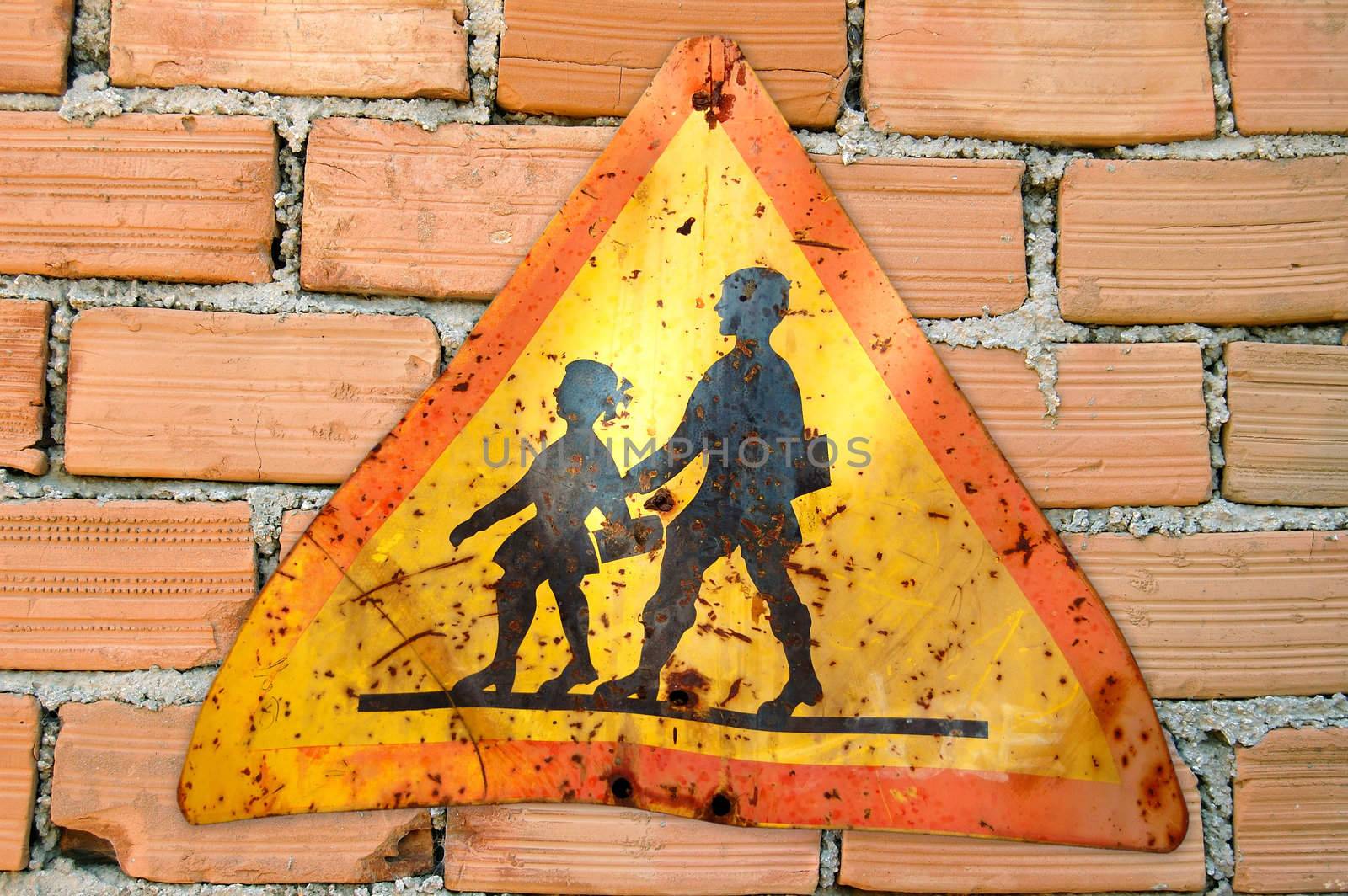 Brick wall and rusty warning sign for school children.
