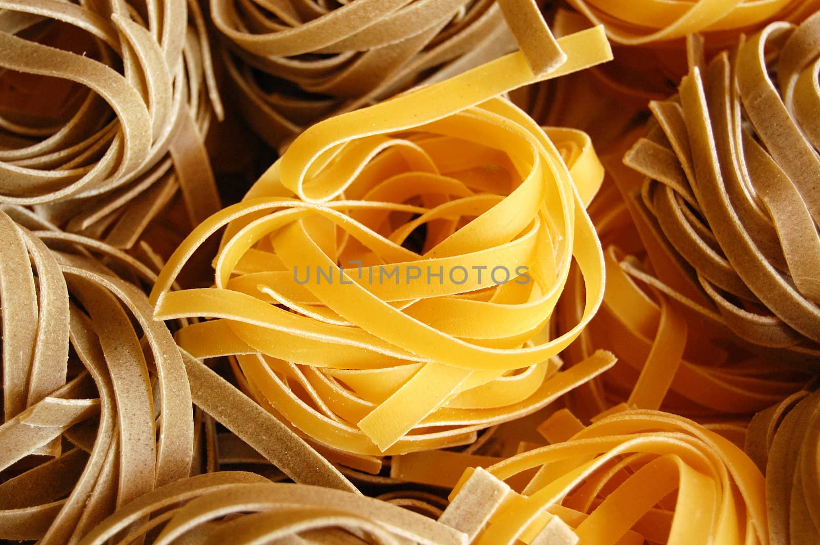 Two flavors of fresh tagliatelle pasta. Italian food background.