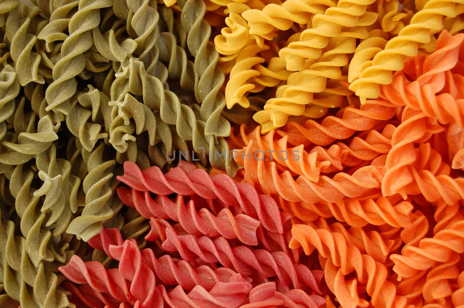 Four different flavors of twirls pasta. Italian food background detail.