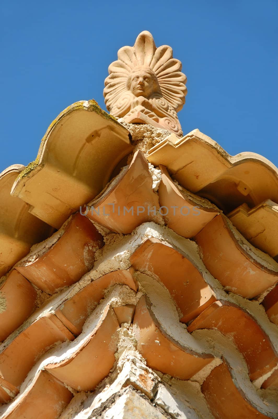 Ceramic antefix decorative ornament on the rooftop of a house in Greece. Architectural detail.