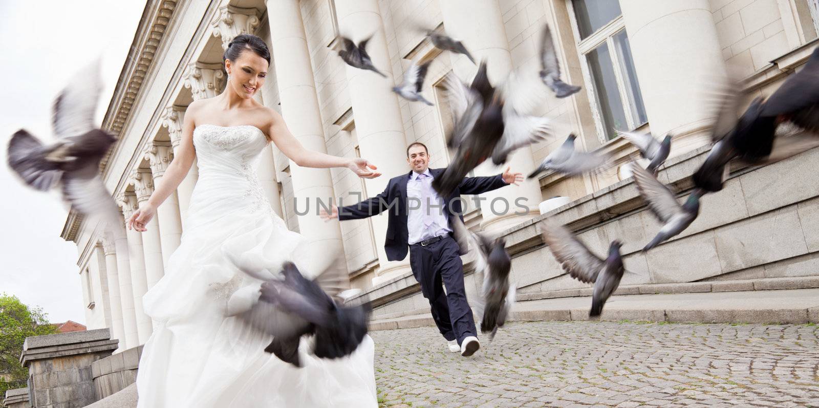 Bride and groom walking behind doves by vilevi
