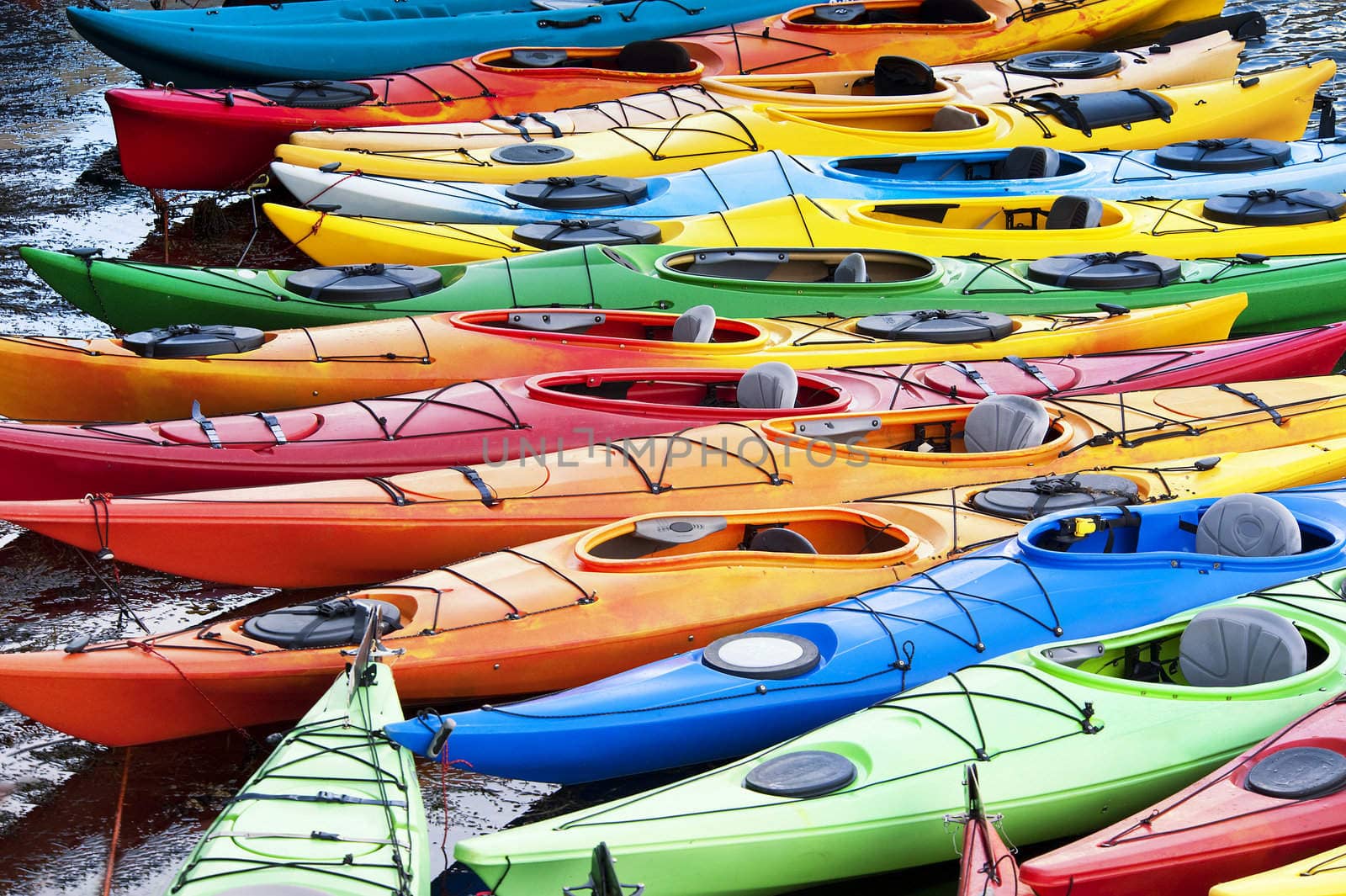 Colorful fiberglass kayaks tethered to a dock as seen from above
