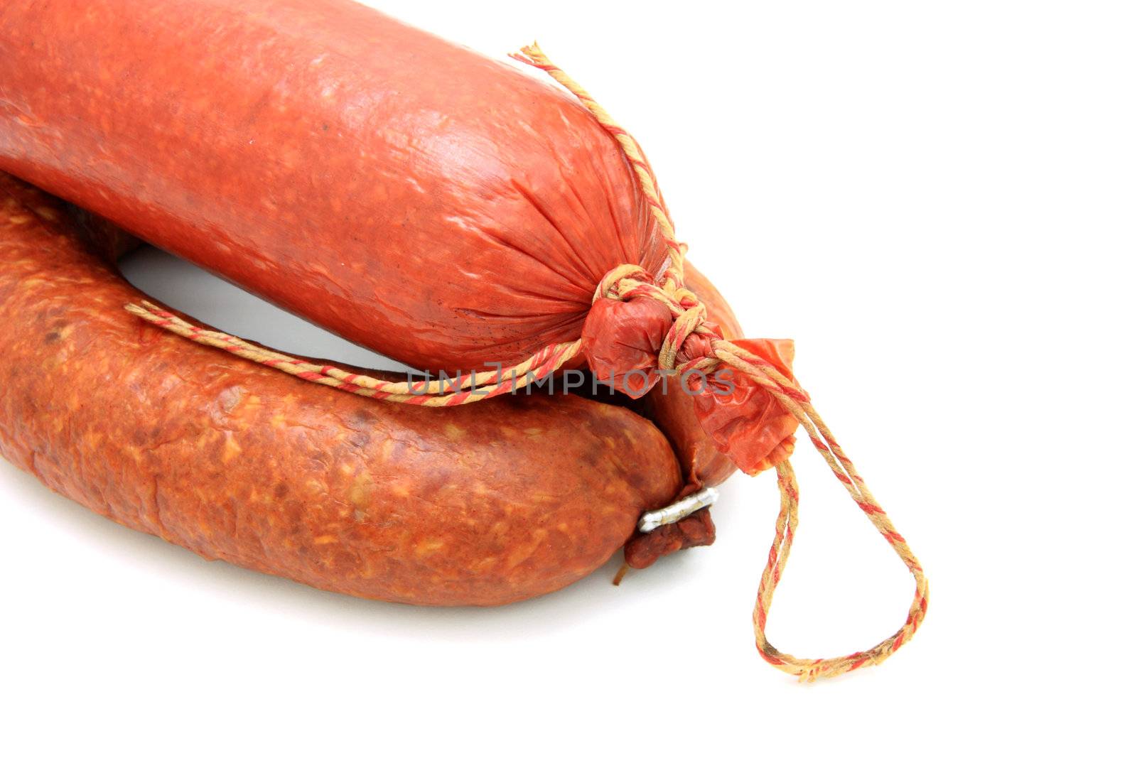 Tasty sausage is curtailed by a ring lies on a white background