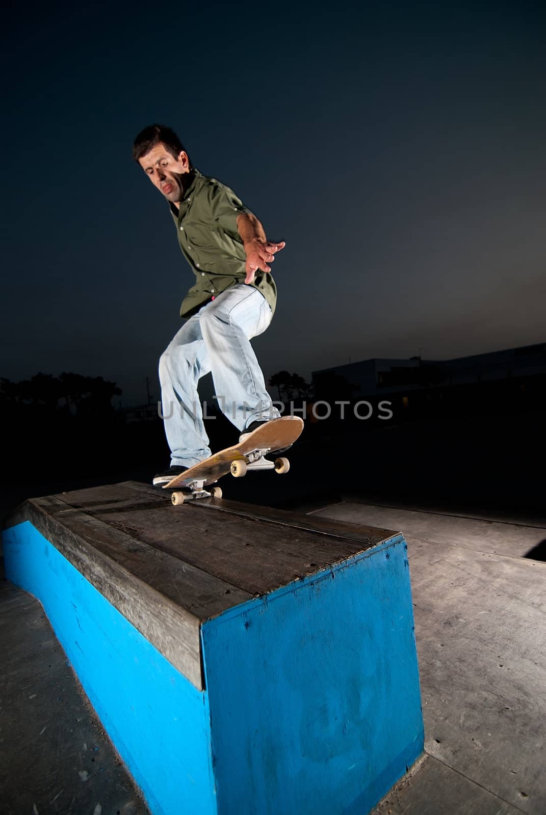 Skateboarder on a grind at night at the local skatepark.