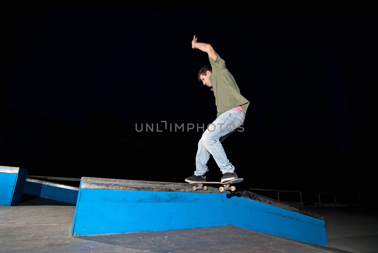 Skateboarder on a slide at night at the local skatepark.