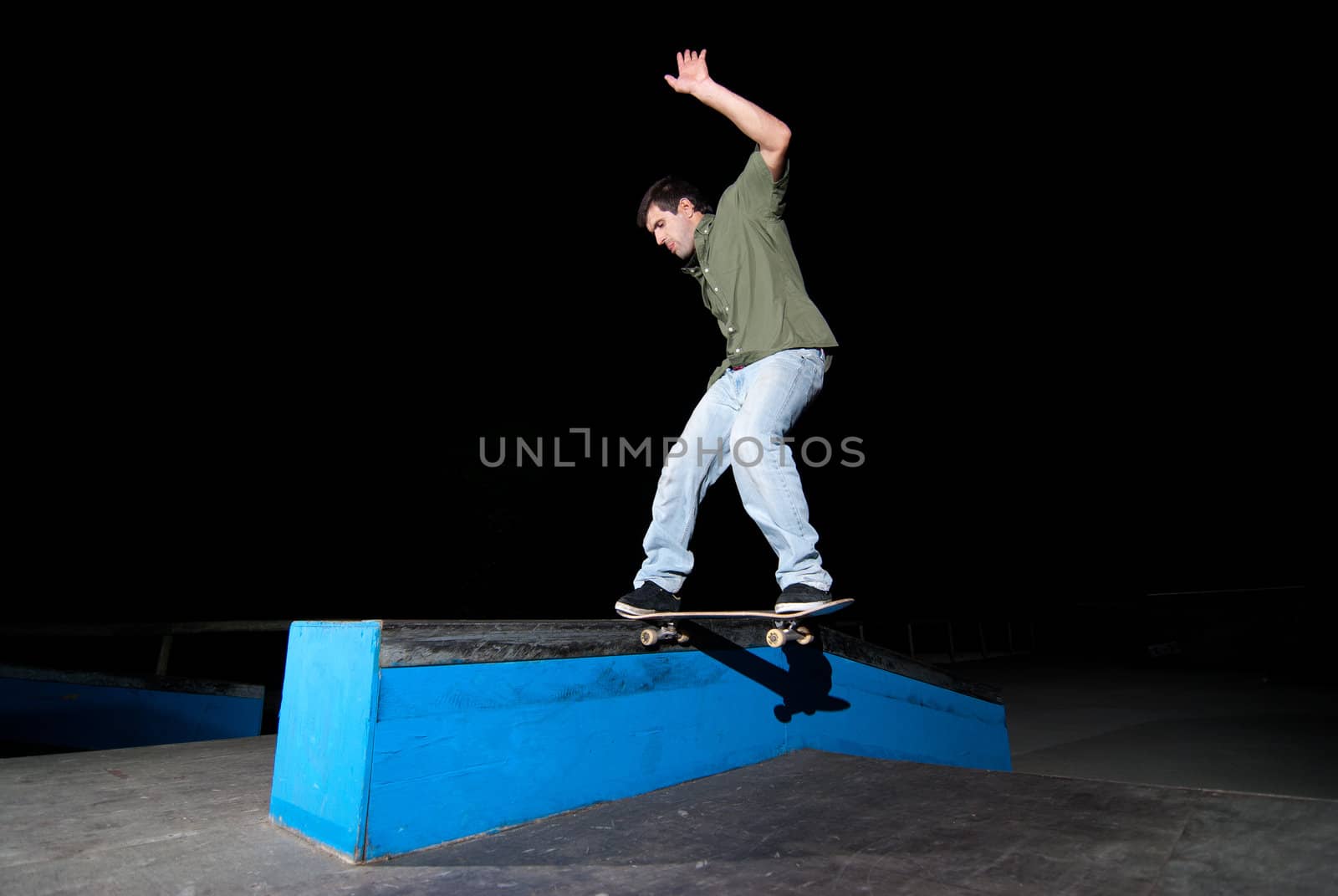 Skateboarder on a slide at night at the local skatepark.