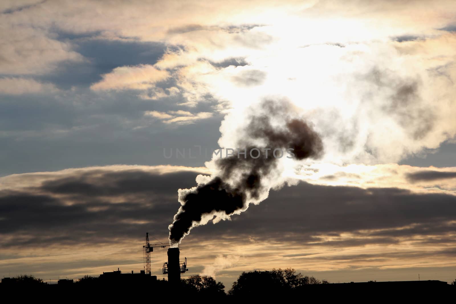 Smoke from factory pipe darkens the sun