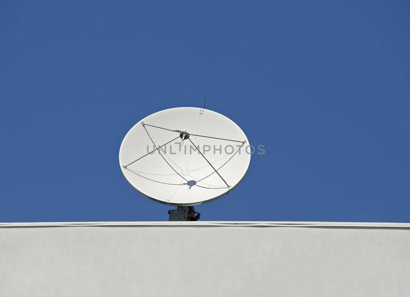 Satellite dish on roof, blue sky background