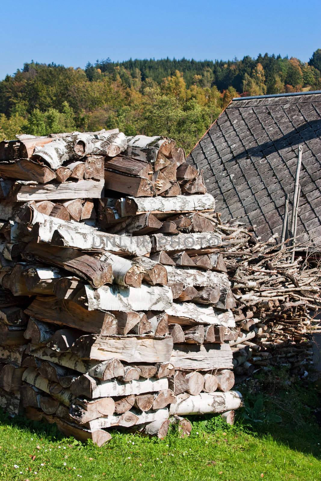 Stock of wooden logs next to a mountain chalet, in anticipation of winter