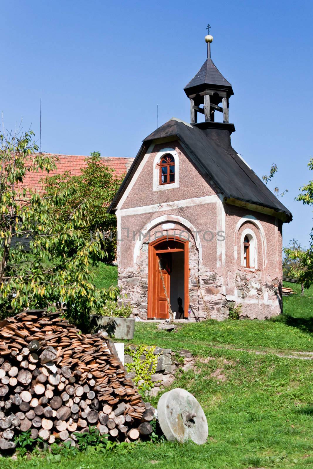 Picturesque landscape with a small chapel and logs of wood in Bohemia