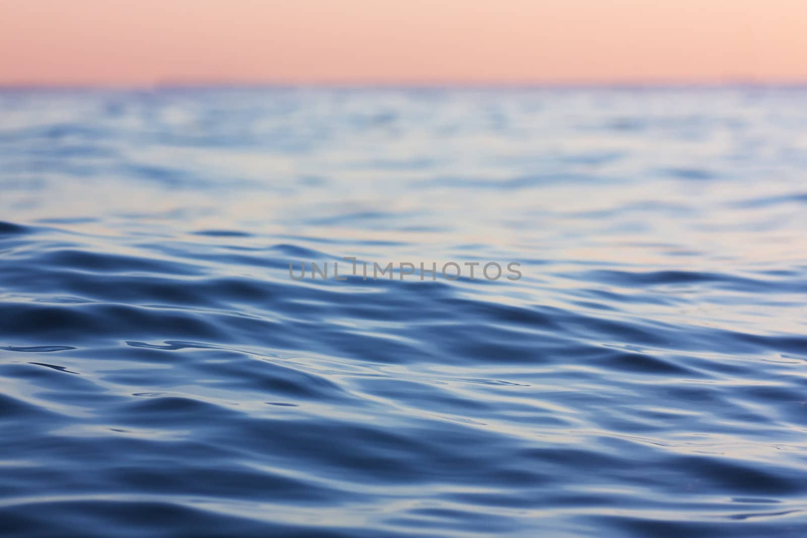 Quiet blue waves in the sea in the sunset light