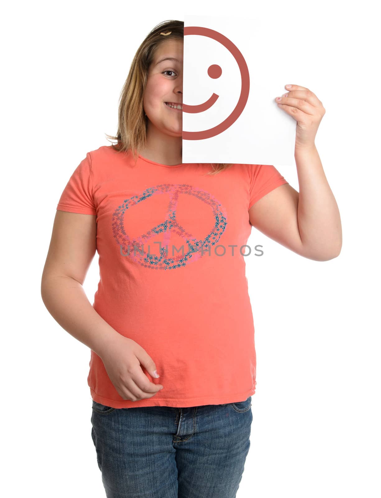 A happy smiling girl is holding up a white piece of paper with half a happy face on it.