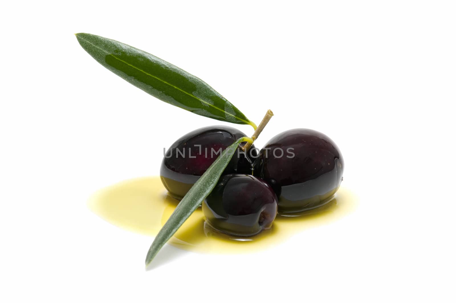 three fresh olives bathed in olive oil on white background