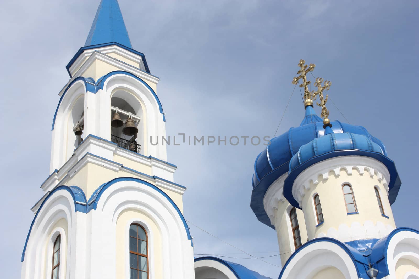Church white with blue domes bells and gold crosses against the blue sky