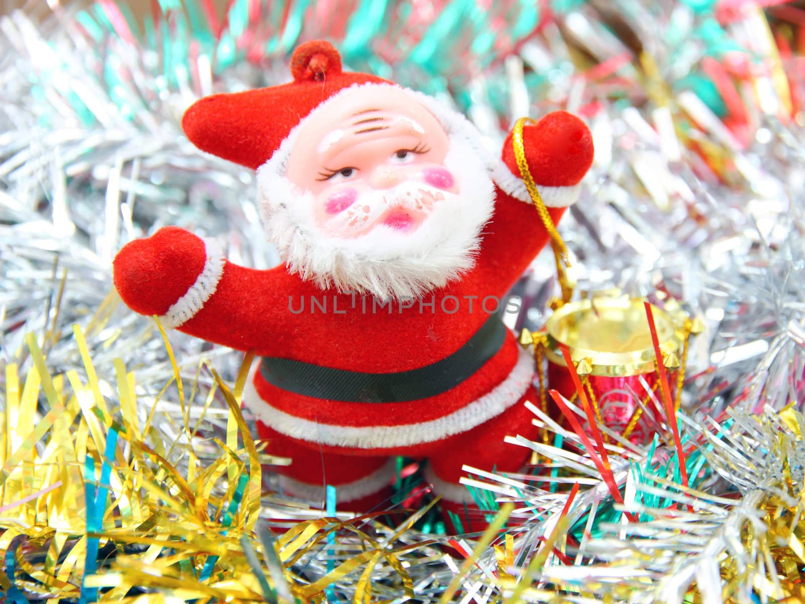 Doll of Santa Claus with a red drum against a tinsel