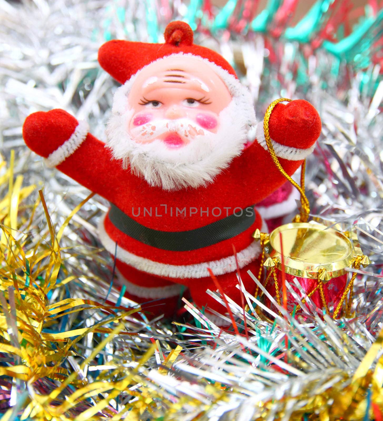 Doll of Santa Claus with a red drum against a tinsel
