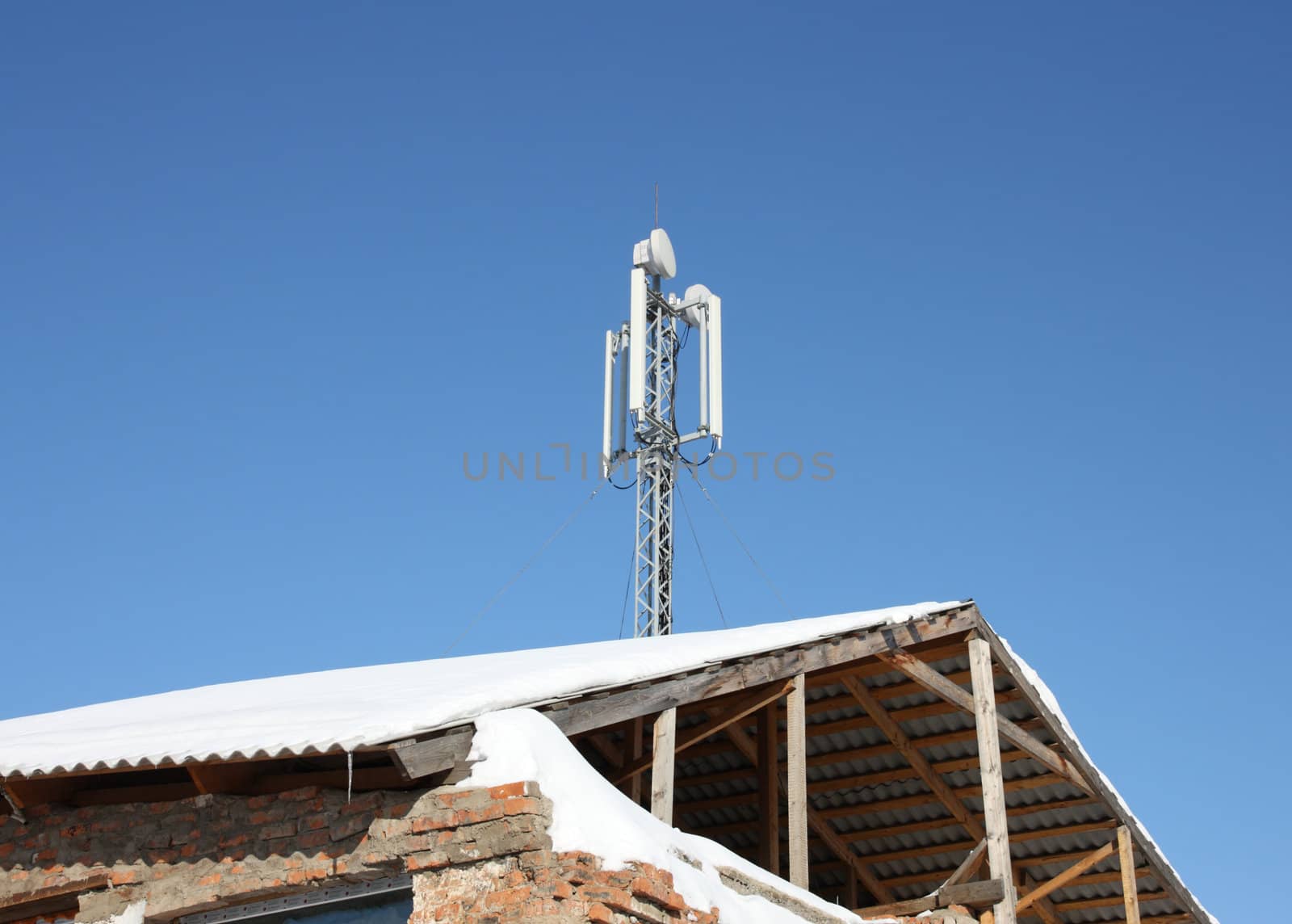 Aerial mobile communication on a roof of the old house against the blue sky